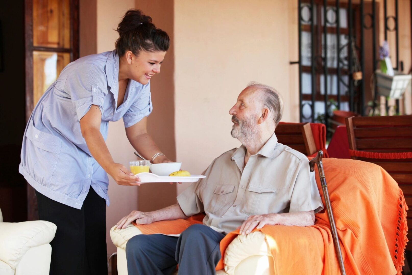 Caregiver serving meal to elderly man.