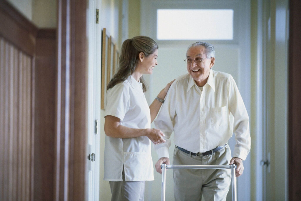 Elderly man with walker and caregiver smiling.