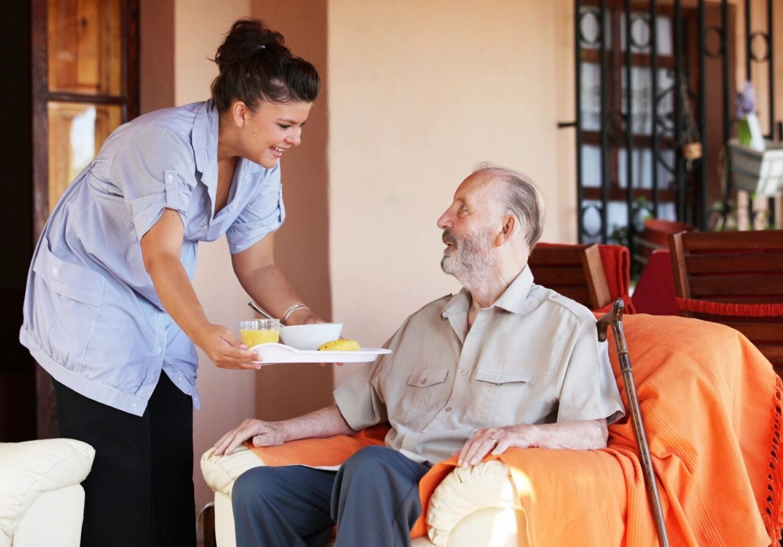 Caregiver serving meal to elderly man.