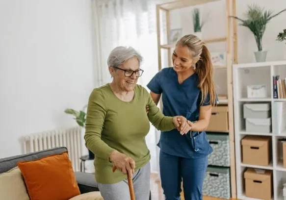 Caregiver assisting elderly woman walking with cane